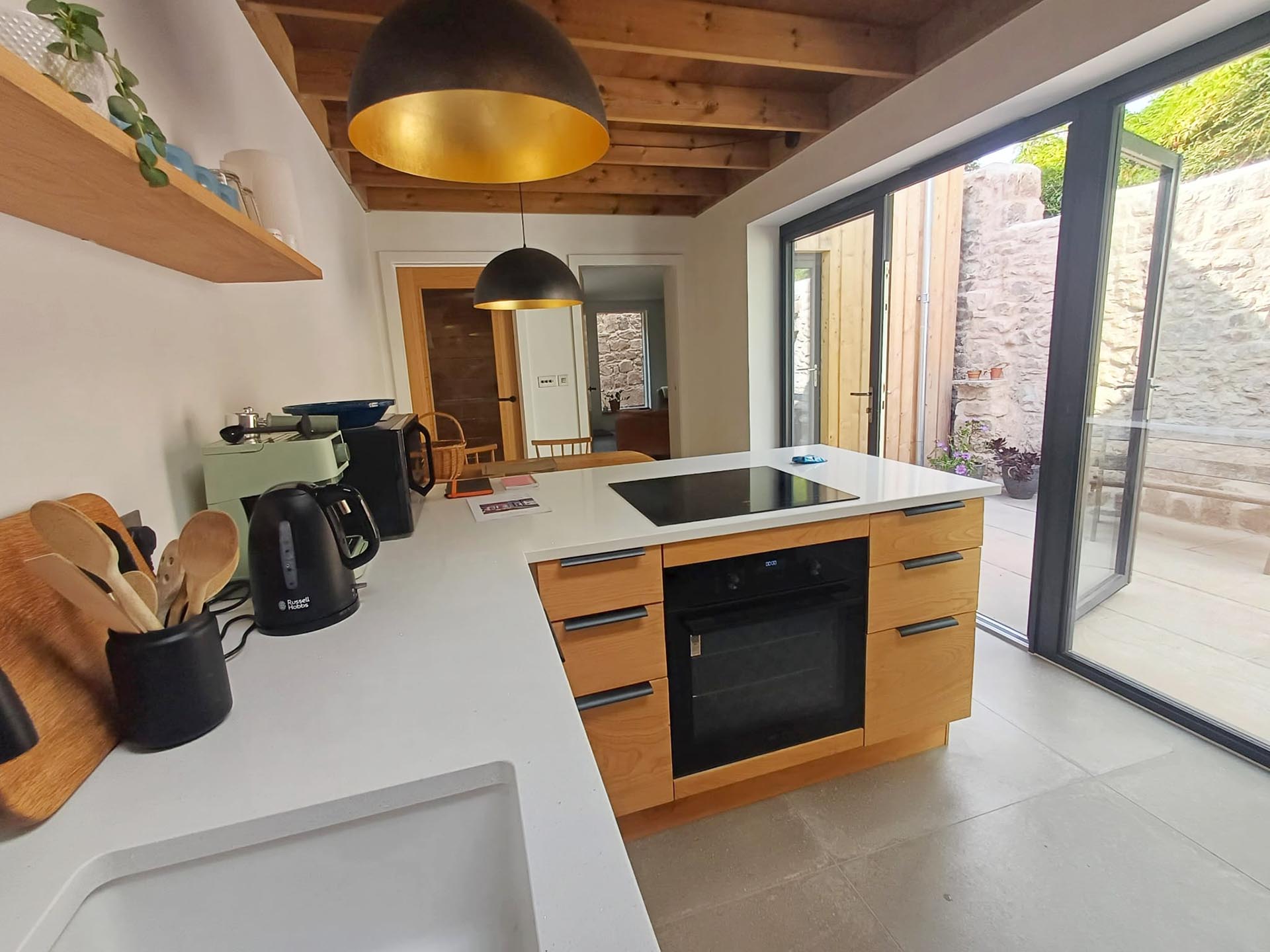 Light, airy bespoke kitchen with sweet chestnut drawers & view through patio doors to courtyard at Fernleigh Courtyard.