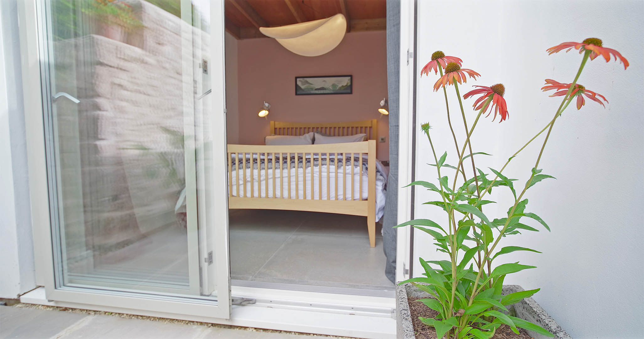 The ground floor bedroom with king size bed seen through sliding door from the courtyard at Fernleigh Courtyard holiday cottage.