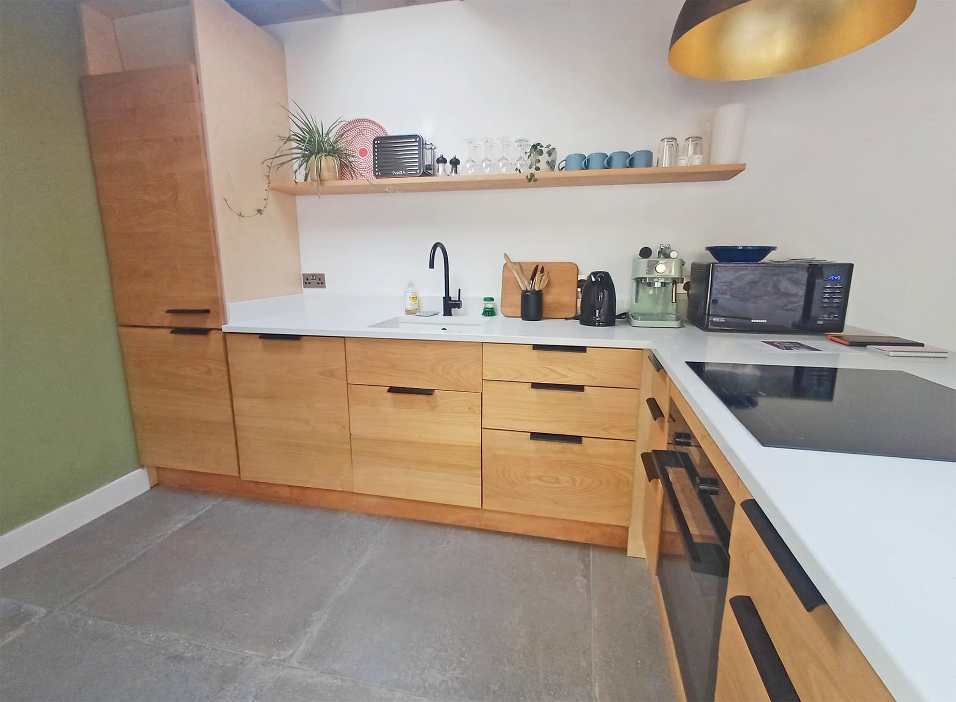 Hand-made sweet chestnut fronted kitchen units with oven and induction hob at Fernleigh Courtyard luxury holiday cottage.
