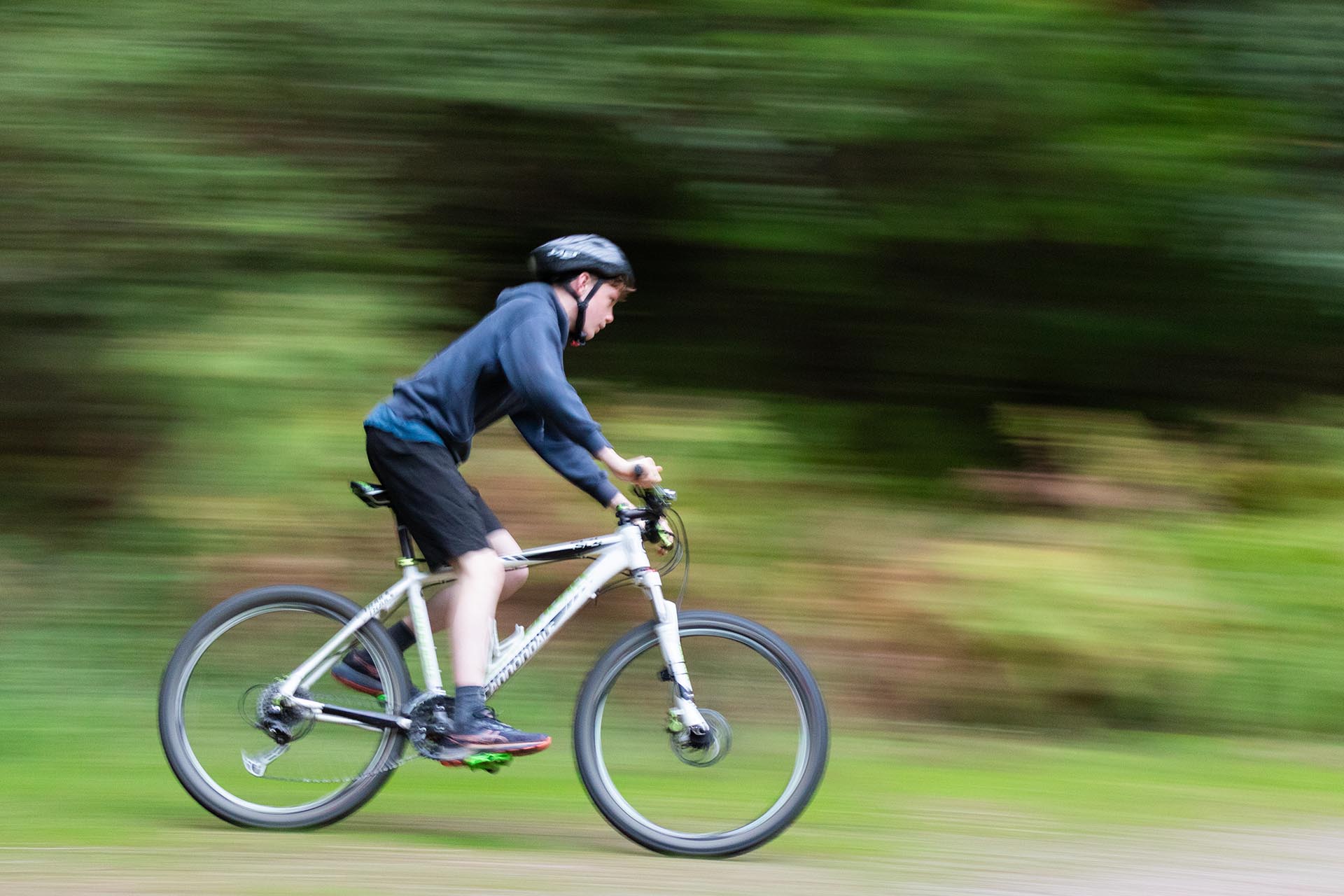 A young mountain biker at speed mountain biking on trails in the Forest of Dean.